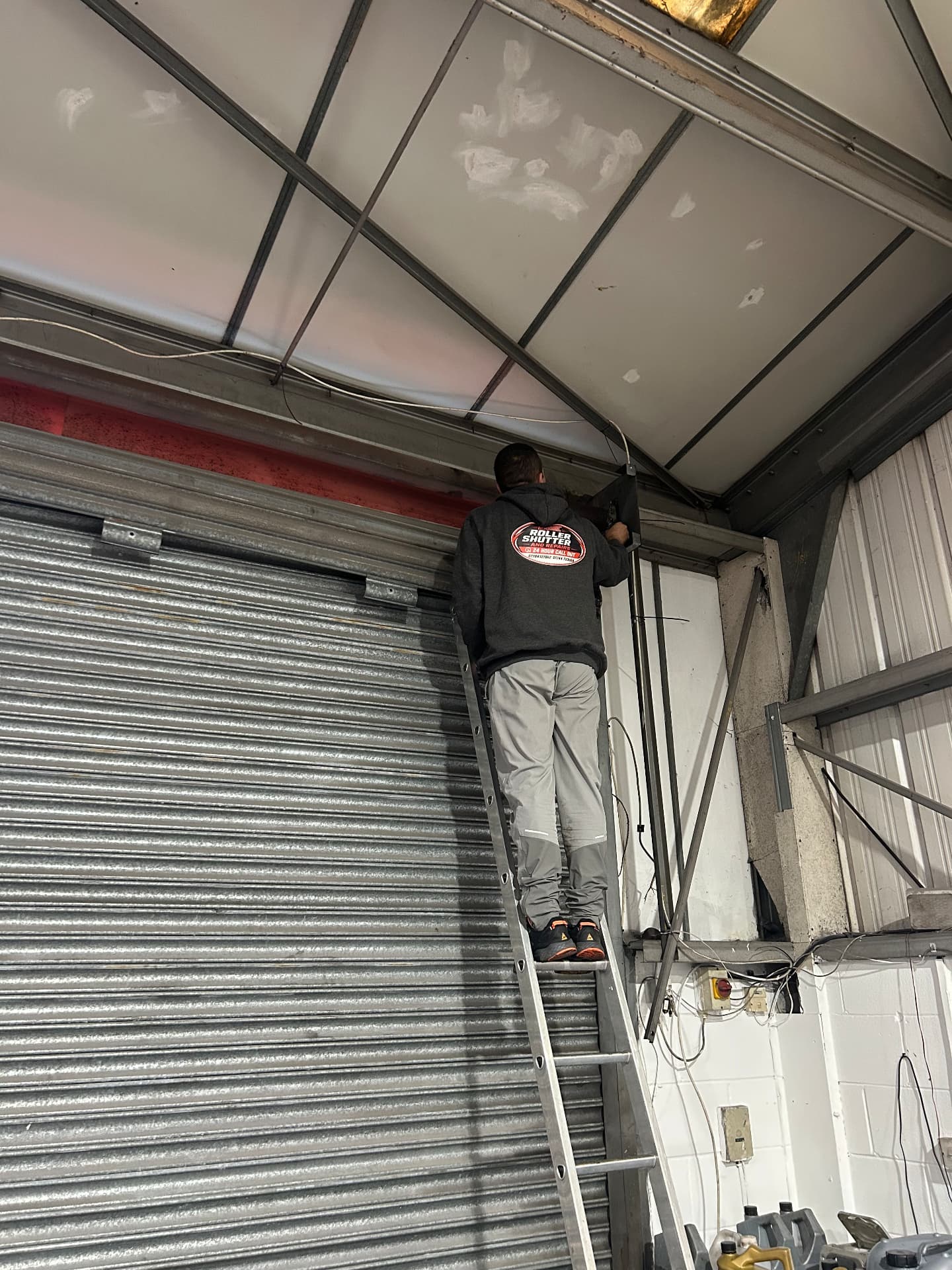Excel engineer working on a roller shutter above a doorway